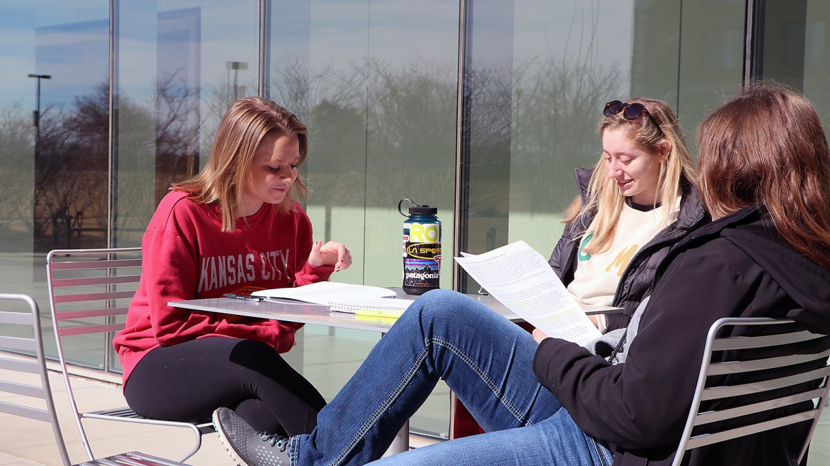 Three students working together at a table outside