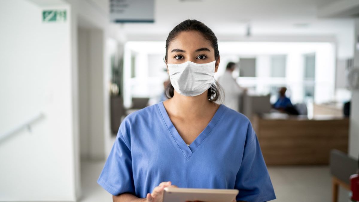 Person wearing scrubs and mask in a healthcare setting