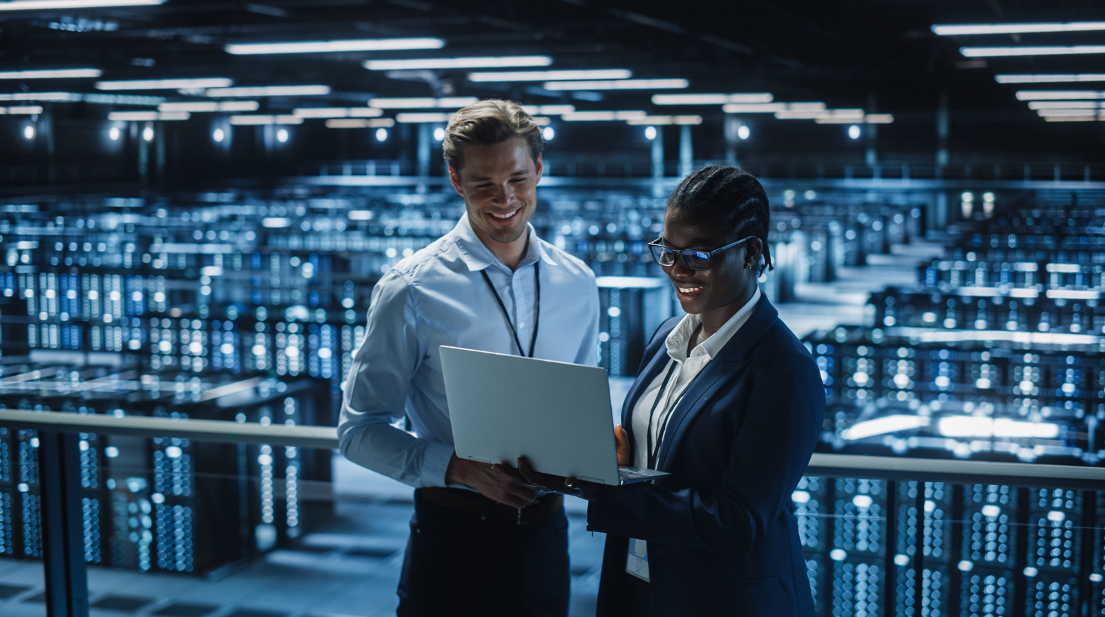 Two people standing in front of computer servers talking 