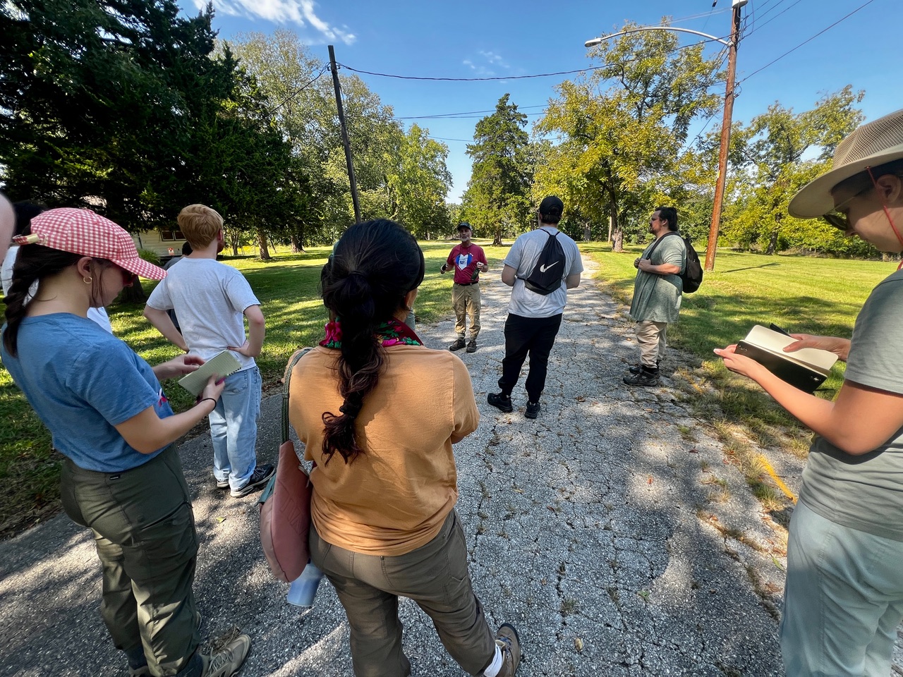 KU Environmental Assessment graduate students take notes as an instructor speaks during an urban natural resources field site visit in Kansas City.