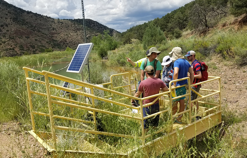 Ron Parratt, guest lecturer from Newmont Mining Corp., explains a telemetric system to KUEC hydrogeology students. This system controls the amount of water that is transferred from a contaminated pond to a treatment system (the ponds behind them in the photo). The Cripple Creek & Victor gold mine releases water that must be treated before it enters Four Mile Creek.