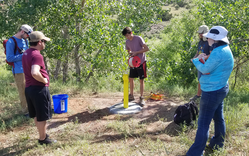 Hydrogeology students at the Robert P. Harrison Field Station are measuring the water level in their newly-installed groundwater monitoring well using an electric water-level tape.