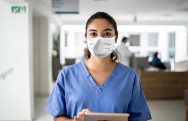 Person wearing scrubs and mask in a healthcare setting