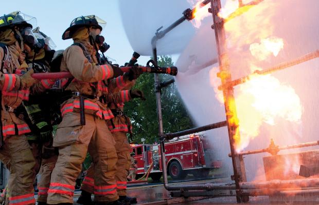 Firefighter trainees fight a controlled fire during an exercise